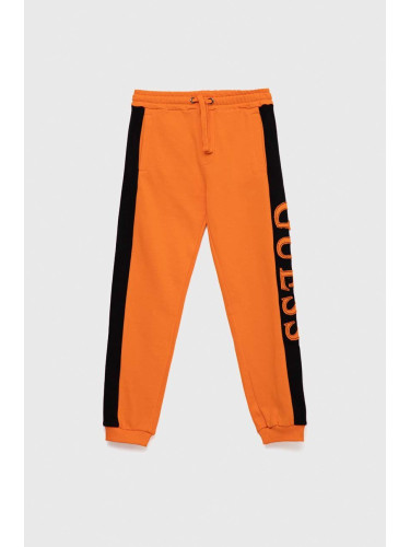 Детски памучен спортен панталон Guess в оранжево с апликация