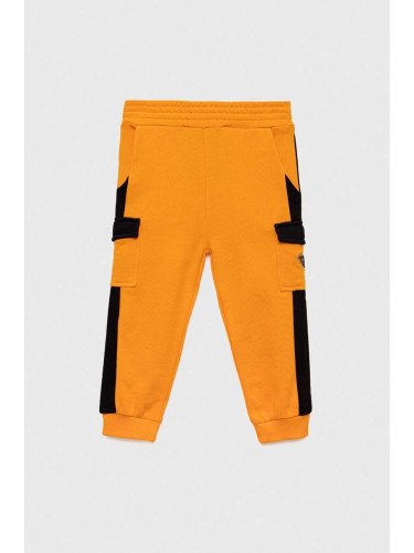 Детски памучен спортен панталон Guess в оранжево с десен