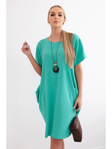Loose, dark mint dress with pockets and a pendant